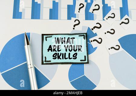 Konzept der Geschäftsfrage. Auf den blauen Diagrammen befinden sich ein Stift, Fragen und ein Aufkleber mit der Aufschrift „Was sind Ihre Fähigkeiten?“ Stockfoto