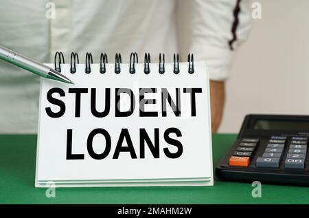 Geschäftskonzept. Auf einer grünen Oberfläche steht ein Taschenrechner, ein Mann zeigt mit einem Stift auf ein Notizbuch mit der Aufschrift Studentendarlehen Stockfoto