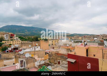Fez, Marokko - Tagesaussicht auf die Dächer der Wohngegend von der Medina von Fes el Bali. Stadtgebäude und Berge dahinter. Horizontaler Reisehintergrund, Stadtbild. Stockfoto
