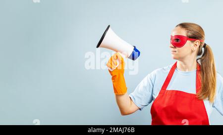 Frau in roter Maske, Handschuhen und Schürze mit Megaphon auf blauem Hintergrund Stockfoto