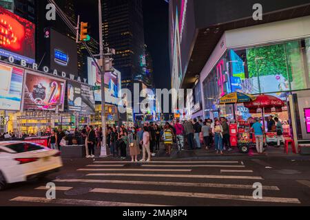 Wunderschöne Aussicht auf den Broadway bei Nacht mit Wolkenkratzern, Autos und Wanderern, die Fußgängerübergänge überqueren. USA. New York. Stockfoto