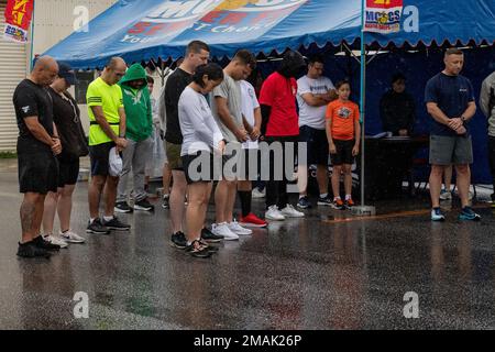 Mitglieder des US-Dienstes und Status der Streitkräfte, die sich für die Beschwörung vor dem Memorial Day 5k Fun Run Run Run in Gunner's Gym, Camp Foster, Okinawa, Japan, am 28. Mai verneigen, 2022. Der „Memorial Day 5k Fun Run“ ist eine jährliche Veranstaltung, die von Marine Corps Community Services zu Ehren gefallener US-Mitglieder in Ausübung ihres Dienstes abgehalten wird. Stockfoto