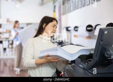 Der Techniker wechselt das Papier auf der Plottermaschine des Druckers Stockfoto