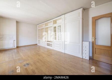 Wohnzimmer eines leeren Hauses mit Eichentüren und einem maßgeschneiderten, weiß lackierten Holzregal Stockfoto