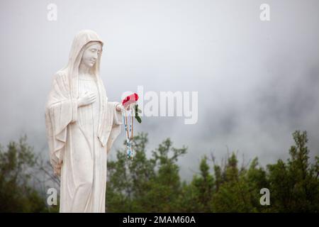 Statue der seligen Jungfrau Maria auf dem Berg Podbrdo, dem Erscheinungsberg mit Blick auf das Dorf Medjugorje in Bosnien und Herzegowina. Stockfoto