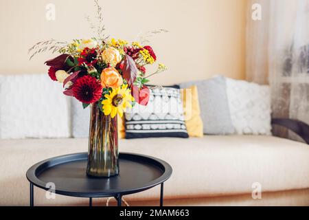 Blumenarrangement auf dem Tisch. Nahaufnahme von Herbststrauß von Sonnenblumen Dahlien Rosen und Zinnien in Vase zu Hause. Stockfoto