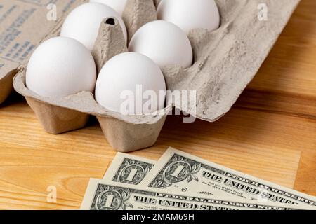 Frische weiße Hühnereier in einem Karton mit Bargeld. Eierpreis, Lebensmitteleinkauf und Geflügelzuchtkonzept. Stockfoto