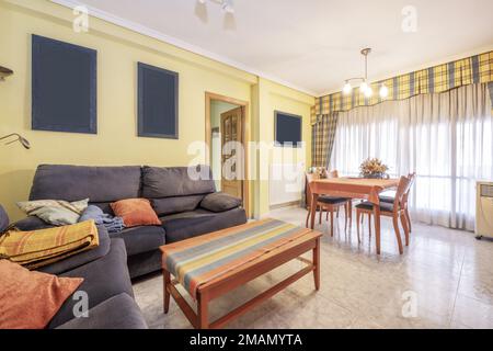 Wohnzimmer eines Hauses mit blauen Stoffsesseln und Kirschholzkaffee und Esstisch Stockfoto