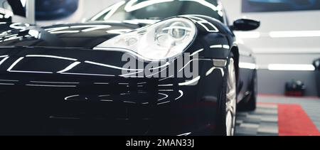 Die Vorderseite des Sportwagens. Innenaufnahme eines schwarz glänzenden Sportfahrzeugs während der Renovierungsarbeiten und der Fahrzeugaufbereitung. Hochwertiges Foto Stockfoto