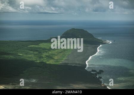 Wellen stürzen in die vulkanischen Aschestraßen unter dem Mt. Suribachi, die bekannteste Sehenswürdigkeit der Insel Iō Tō (Iwo Jima) und der Ort der berühmten US-amerikanischen Marinekorps-Flagge am 23. Februar 1945. Marines aus mehreren Einheiten, die der 3. Marine Expeditionstruppe zugeteilt wurden, gingen am Memorial Day Wochenende nach Iwo Jima, um die Marines des 2. Weltkriegs zu ehren Stockfoto