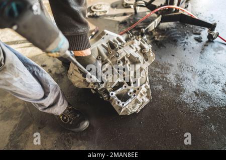 Mechaniker mit Handschuhen ersetzt die Kupplungsscheibe des Getriebes im Fahrzeug an der Tankstelle. Hochwertiges Foto Stockfoto