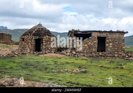 Steinhütten, die im Sommer von Schafen im Hochland von Lesotho genutzt werden. Stockfoto