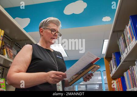 Holly Keene-Steele, eine Bibliothekstechnikerin, durchsucht ihre Liste mit Kinderbüchern, die sie in einem Wagen in der John L. Throckmorton Library in Fort Bragg, North Carolina, am 1. Juni 2022 aufbewahren kann. Bücher, die für Kinder als leichter lesbar gelten, werden häufig aus der Kinderabteilung herausgenommen und später an der Rezeption der Bibliothek für Eltern organisiert. Stockfoto