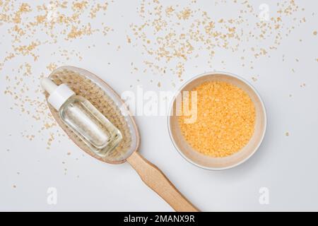 Ein Holzlöffel mit etwas Zucker drauf neben einer kleinen Schüssel gefüllt mit Hafer und Goldflocken Stockfoto