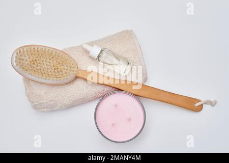 Eine Holzbürste und ein weißes Handtuch neben einer pinkfarbenen Zahnbürste auf weißem Hintergrund mit Kopierbereich in der oberen rechten Ecke Stockfoto