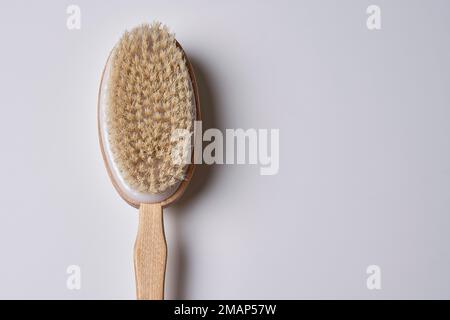 Eine Holzzahnbürste auf weißem Hintergrund mit Kopierbereich in der unteren rechten Hand hält sie bis zum Griff Stockfoto