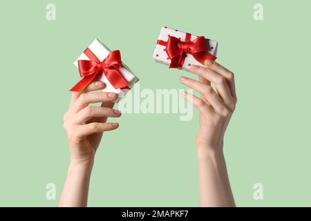 Eine Frau mit Geschenkschachteln und einer wunderschönen Schleife auf grünem Hintergrund. Valentinstag-Feier Stockfoto