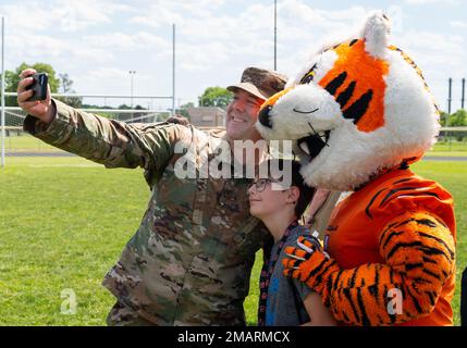 Oberst Patrick Miller, 88. Luftwaffenstützpunkt und Installationskommandeur, und sein Sohn Adam posieren für ein Selfie mit Who Dey, dem Maskottchen der Cincinnati Bengals, nach einer VON DER USO gesponserten bengalischen Fachklinik am 3. Juni 2022 auf dem Luftwaffenstützpunkt Wright-Patterson, Ohio. Who Dey schloss sich einer Gruppe bengalischer Neulinge an und arbeitete mit 99 Wright-Patt-Kindern an ihren Fußballfertigkeiten. Stockfoto