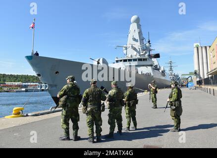 220605-N-BP933-1385 STOCKHOLM (5. Juni 2022) Mitglieder der schwedischen Hauswache stehen an der Pier-Seite vor dem gewagten Luftschutzzerstörer HMS Defender (D 36) auf Cruise Pirs Frihamn, Stockholm während Übung BALTOPS22, 5. Juni 2022. BALTOPS22 ist die wichtigste maritime Übung im Ostseeraum. Die Übung, geleitet von den USA Die Marinestreitkräfte Europa-Afrika, die von den Streik- und Unterstützungskräften der Marine NATO exekutiert werden, bieten eine einzigartige Ausbildungsmöglichkeit zur Stärkung der kombinierten Reaktionsfähigkeiten, die für die Wahrung der Freiheit der Schifffahrt und der Sicherheit in der Ostsee von entscheidender Bedeutung sind. Stockfoto
