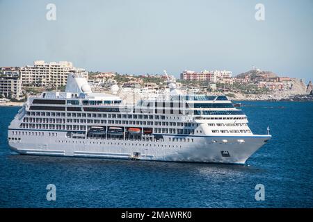 Im Hafen von Cabo San Lucas, mexikanische Riviera, Mexiko, liegt ein Kreuzfahrtschiff vor Anker. Cabo ist im Hintergrund. Stockfoto