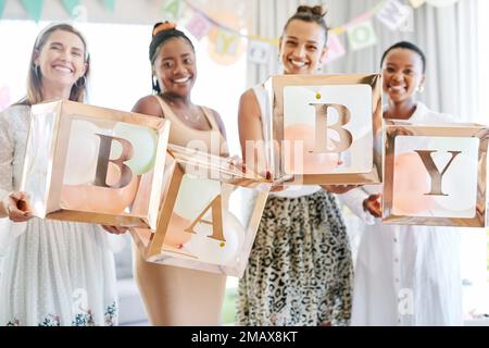 Wir können es kaum erwarten, Ihr Kind kennenzulernen. Eine Gruppe Frauen mit einem Schild auf einer Freundinnen-Babyparty. Stockfoto