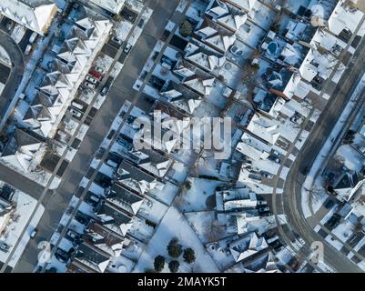 Ein von oben nach unten gerichtetes, direktes Luftfoto hoch über schneebedeckten Häusern, einer großen Wohngegend. Stockfoto