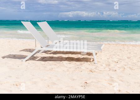 Zwei freie Sonnenliegen stehen an einem sonnigen Tag am weißen Sandstrand, Dominikanische Republik, Bavaro Beach Stockfoto