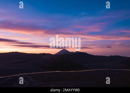 Blick von oben, atemberaubender Panoramablick auf den Mt Batok, Mt Bromo und Mt Semeru in der Ferne beleuchtet während eines dramatischen Sonnenaufgangs. Stockfoto