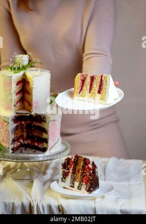 Das Mädchen schneidet und serviert ein Stück Kuchen. Festliche Hochzeit zweistufiger Kuchen mit frischen Blumen dekoriert Stockfoto