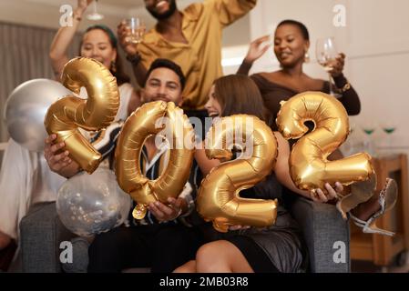Alles Gute Zum 2022. Eine vielfältige Gruppe von Freunden, die während einer Silvesterparty zusammenstehen und 2022 Ballons halten. Stockfoto
