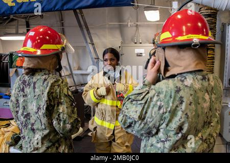 Der Schadenskontrolleur Kyla Embry der Klasse 3., dem Zerstörer der Zumwalt-Klasse USS Michael Monsoor (DDG 1001) zugeteilt, unterrichtet die USA Marine Sea Cadets wie man während der Portland Fleet Week 2022, Juni 9, einen Feuerwehrhelm ordnungsgemäß an Bord des Schiffes trägt. Die Portland Fleet Week ist eine feierliche Feier der Seeverkehrsdienste und bietet den Einwohnern Oregons die Gelegenheit, Matrosen, Marines und Küstenwachmänner zu treffen und die neuesten Möglichkeiten der heutigen Seeverkehrsdienste aus erster Hand zu erleben Stockfoto