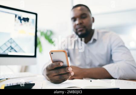 Scrollen derzeit durch verschiedene Social-Media-Plattformen gleichzeitig. Ein junger Geschäftsmann, der ein Handy in einem Büro benutzt. Stockfoto