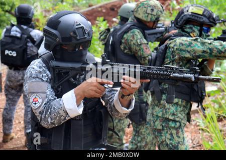 Ein Mitglied der philippinischen Spezialeinsatzkräfte der Küstenwache und seine Partner der philippinischen Nationalpolizei – Maritime Group, 2. Spezialeinsatzeinheit nähern sich ihrem Ziel und demonstrieren dabei eine Razzia, die Generalmajor Valeriano de Leon und Green Berets mit der 1. Special Forces Group (Airborne) am 9. Juni 2022 gesehen haben. In der Nähe von Puerto Princesa, Palawan. Dieses Engagement bot den Partnern die Möglichkeit, Taktiken, Techniken und Verfahren untereinander auszutauschen, um die Interoperabilität zu verbessern und gleichzeitig ihre Fähigkeiten zu demonstrieren. Unsere Verbündeten und Partner sind unser größter Vorteil, wenn Stockfoto