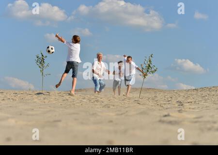 Familie Fußball spielen auf einem Strand im Sommer Tag Stockfoto