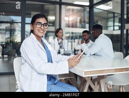 Ich nehme mein digitales Tablet überallhin mit. Eine junge Ärztin, die ihr digitales Tablet benutzt. Stockfoto