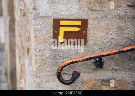 Gelbe Farbe mit einem Schild für Wanderwege, das darauf hinweist, dass die Steine des Treppenwegs erklommen werden Stockfoto