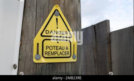 Danger Poteau ein Remplacer-Schild auf französisch bedeutet Gefahr und Pol muss ersetzt werden durch hölzernen Telefonmast Stockfoto