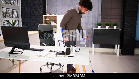 Arbeiter Mit Krücken Am Arbeitsplatz Oder Im Büro. Rehabilitationsleistungen Stockfoto
