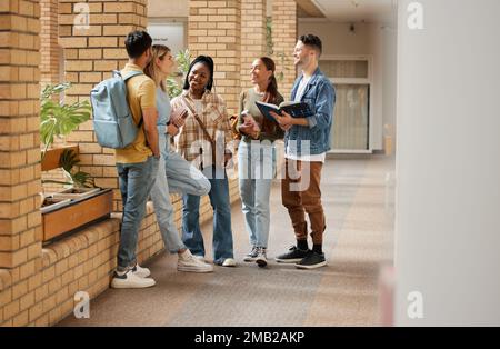 Lernen, Freunde und College mit Studenten, die sich auf dem Campus mit Büchern für Bildung, Stipendium oder Wissen unterhalten. Studium, Zukunft oder Universität mit Stockfoto