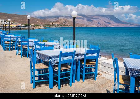 Blaue Tische und Stühle in einer traditionellen griechischen Taverne an der Küste. Kissamos, Kreta, Griechenland Stockfoto