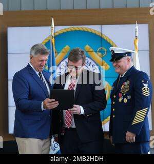 Der 26. Kommandant ADM. Karl Schultz, (ret) Left, überreicht Anthony Bushey, Center, mit einem Preis, Während Master Chief Rob Bushey zusieht, während seiner Ruhestandszeremonie in Washington, D.C., am 10. Juni 2022. Bushey, der als stellvertretender Oberbürgermeister der Küstenwache diente, ging nach mehr als 31 Jahren in den Ruhestand. USA Foto der Küstenwache von Chief Petty Officer Jetta Disco. Stockfoto