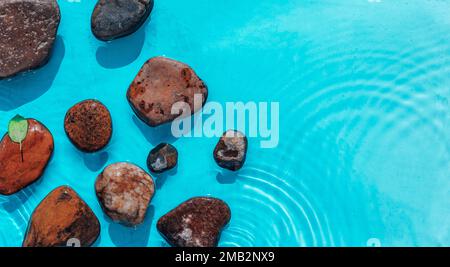 Seesteine im Meerwasser. Kieselsteine unter Wasser. Draufsicht. Stones In Blue Water - Zen-Konzept Stockfoto