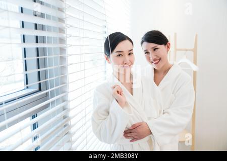 Mutter und Tochter, zwei Leute im Bademantel saßen am Fenster Stockfoto