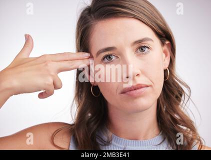 Ich fühle mich leer. Studio-Porträt einer jungen Frau, die eine Waffe mit ihren Händen vor grauem Hintergrund macht. Stockfoto