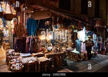 Touristen und Souvenirläden verkaufen Marokkanisches Kunsthandwerk bei Nacht, Granada, Andalusien, Spanien, Europa. Stockfoto