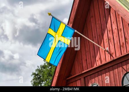 Schwedische Flagge, Nationalflagge auf einem roten hölzernen Giebel, schwedisches Haus, Insel Gotland, Schweden Stockfoto