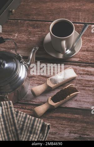 Zenithaler Blick auf eine Kaffeetasse mit Milchkännchen und Holzlöffeln auf einem Holztisch mit Textfläche Stockfoto