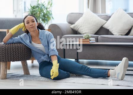 Mann, diese ganze Reinigung hat mich geschlagen. Eine junge Frau ruht sich aus, während sie zu Hause putzt. Stockfoto