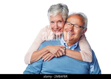 Liebe, Porträt und Seniorenpaar umarmen sich im Studio, lächeln und glücklich zusammen vor weißem Hintergrund. Entspann dich, Gesicht und alter Mann mit weiblicher Umarmung Stockfoto