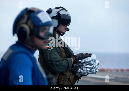 USA Navy LT. Cody Hull, ein Pilot, der der Helicopter Sea Combat Squadron (HSC) 23 zugeteilt ist, liefert das Abendessen an die Besatzung an Bord des amphibischen Angriffsträgers USS Tripoli (LHA 7), während er am 11. Juni 2022 unterwegs ist. Der amphibische Angriffsträger USS Tripoli (LHA 7) führt Routineeinsätze innerhalb der US-7.-Flotte durch. Stockfoto